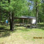 Woodland area with pavilion and portable restroom.