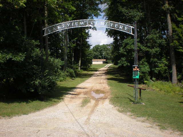 lakeviewsign orig Entrance to cemetery with gravel road and trees.