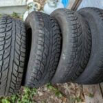 Four stacked used car tires on ground