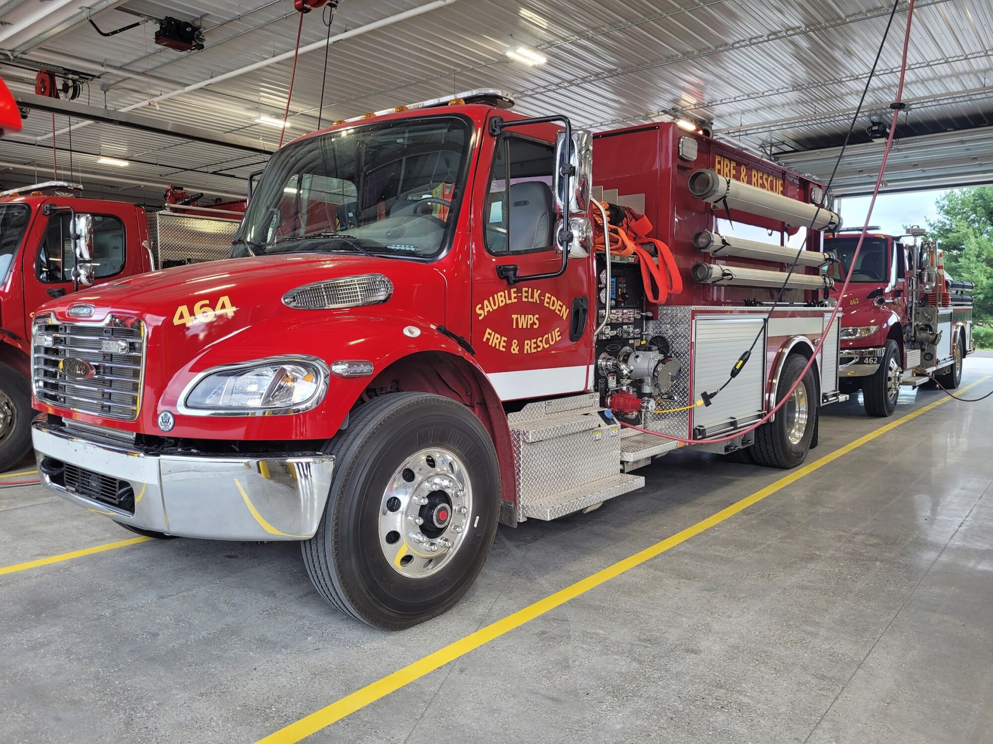 Red fire trucks parked in a station garage.